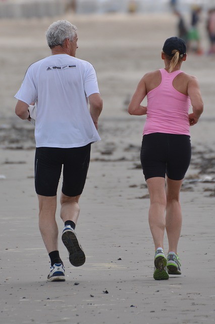 An older man and a middle aged woman run together captured from behind as they run away from the camera. 